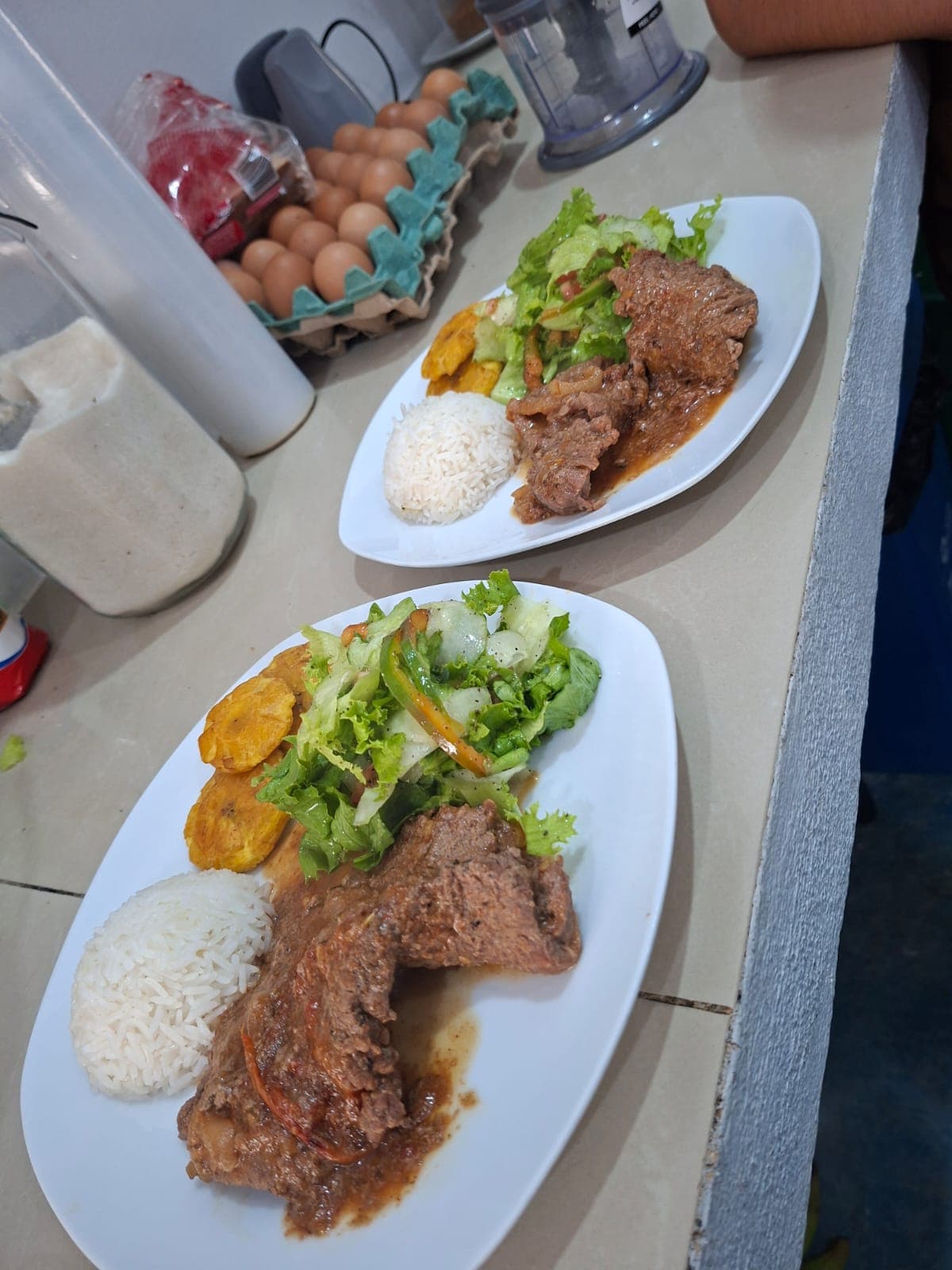 Costa Rican beef stew plated with white rice, fresh salad and sweet plantains