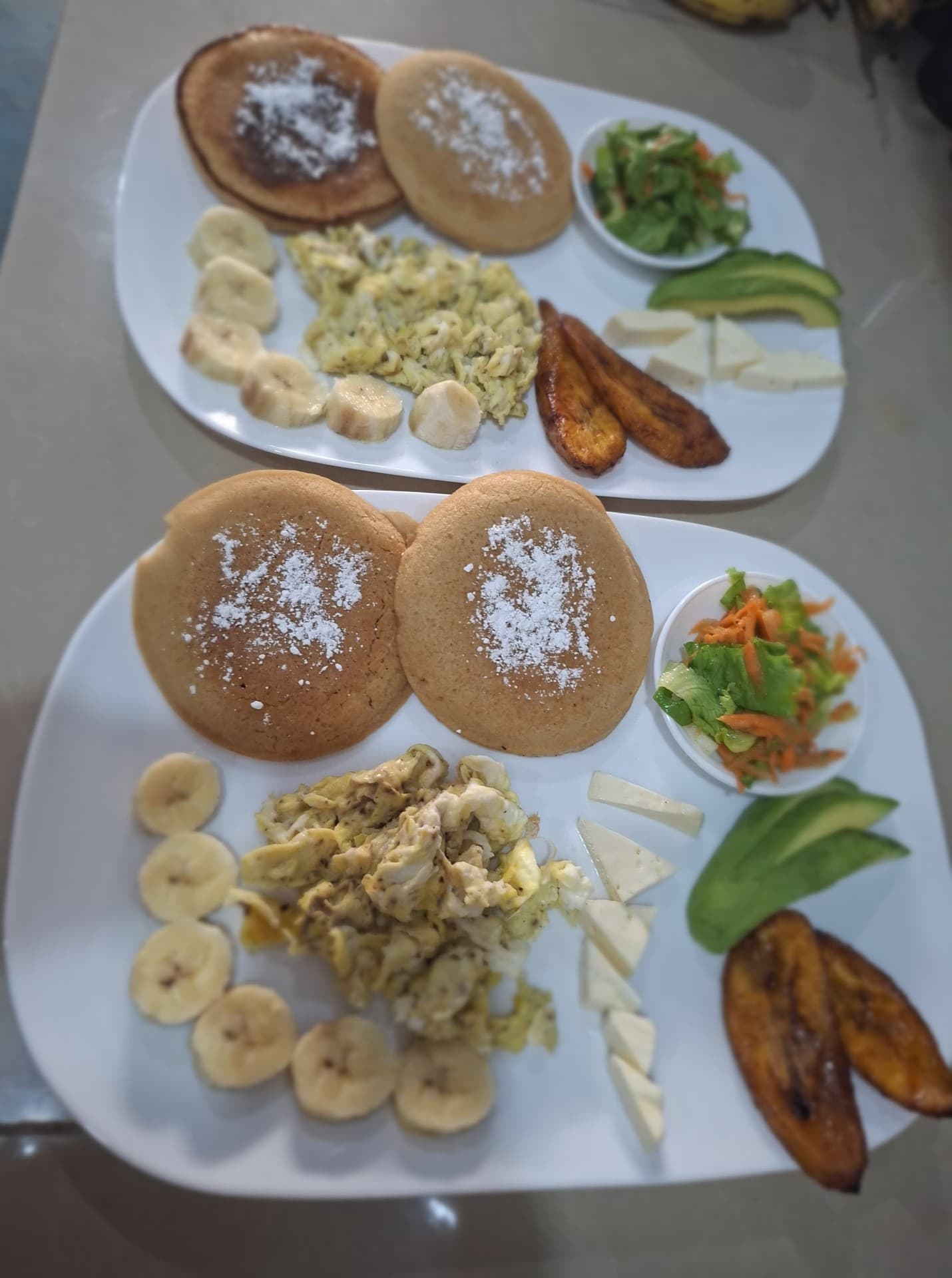 Two breakfast plates with pancakes, eggs, fresh fruit and salad served for couples at Hotel Serendipity