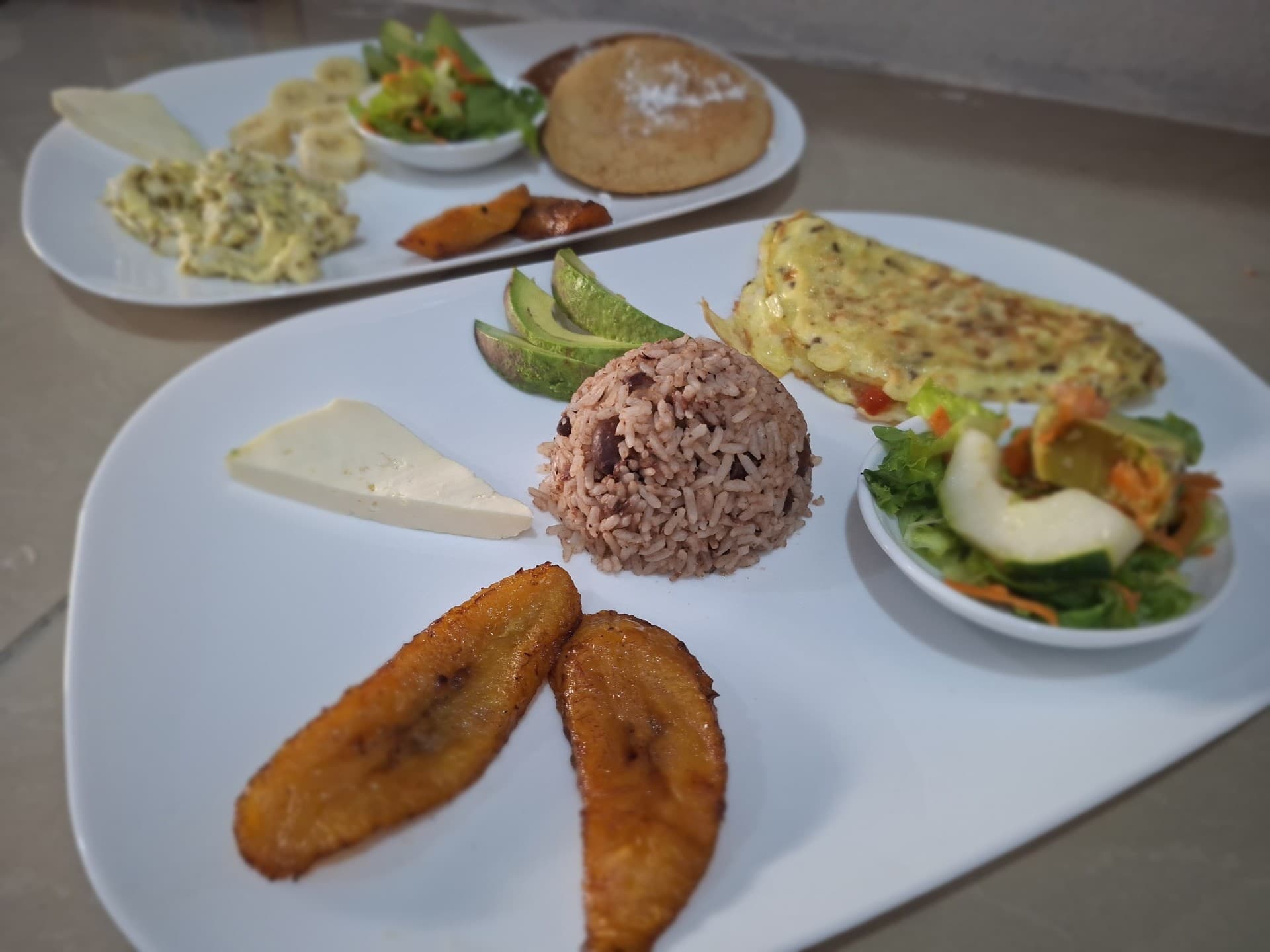 Traditional Costa Rican gallo pinto breakfast with omelet, cheese, avocado and sweet plantains