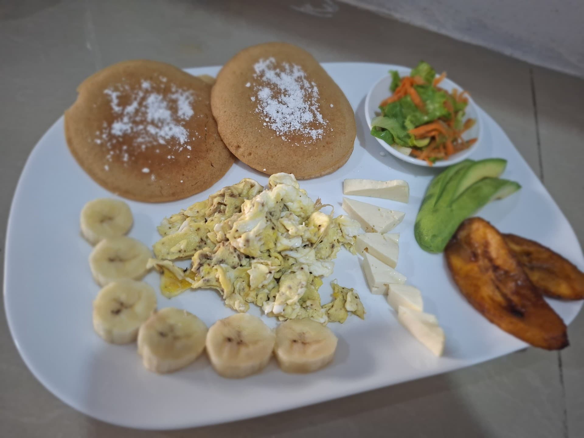 Tico breakfast plate with pancakes, scrambled eggs, banana, fresh cheese, avocado and sweet plantains at Hotel Serendipity Tortuguero