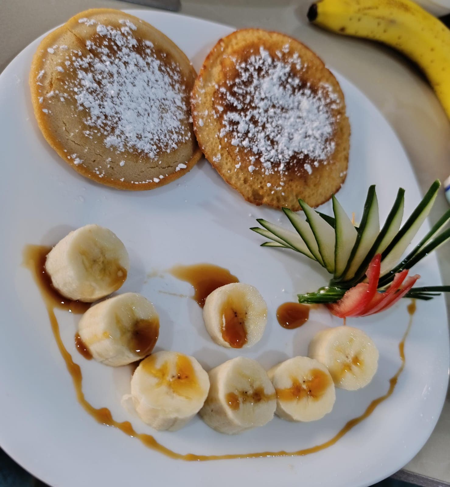 Fluffy pancakes with powdered sugar, fresh banana and caramel sauce for breakfast at Hotel Serendipity